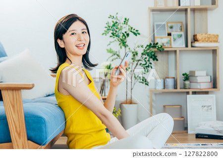一個女人在客廳裡看著她的智能手機 一個女人在客廳裡看著她的智能手機 127822800
