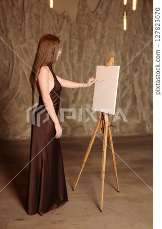 An Elegant and Inspired Artist in a Creative Setting Surrounded by a Blank Canvas Awaiting Mastery 127823070