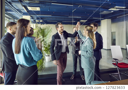 Happy colleagues giving high five at meeting in office, celebrating success or business achievement Happy colleagues giving high five at meeting in office, celebrating success or business achievement 127823633