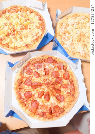 在餐桌上享用三種受歡迎的披薩:薩拉米披薩、蛋黃醬馬鈴薯披薩和海鮮披薩 在餐桌上享用三種受歡迎的披薩:薩拉米披薩、蛋黃醬馬鈴薯披薩和海鮮披薩 127824254