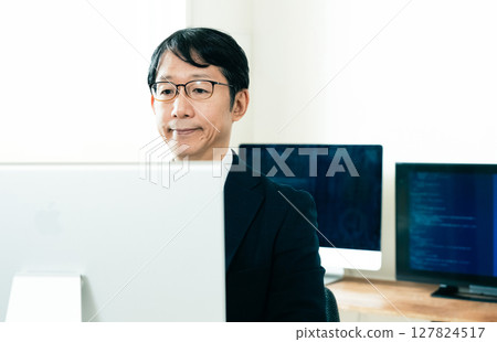 Middle-aged man facing a computer Middle-aged man facing a computer 127824517