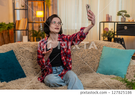 Blogger woman filming vlog stream on smartphone camera at home smiling and interacting with audience 127825186