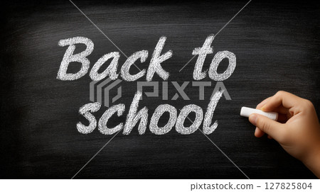 Back to school written in white chalk on blackboard with hand holding chalk 127825804