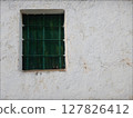 Old green wooden window in an old white facade 127826412