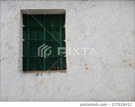 Old green wooden window in an old white facade Old green wooden window in an old white facade 127826412