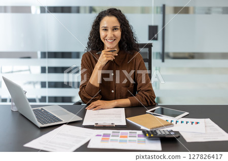 Portrait of a successful businesswoman, financier, accountant. Company employee looking at the camera, working with documents, papers and reports. 127826417
