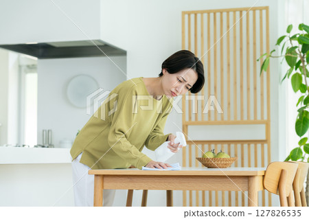 Middle-aged housewife cleaning the table Middle-aged housewife cleaning the table 127826535