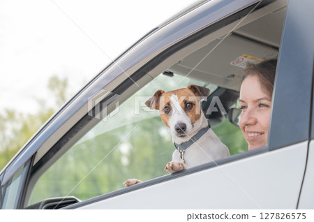 Caucasian woman looking out of car window with dog. Caucasian woman looking out of car window with dog. 127826575