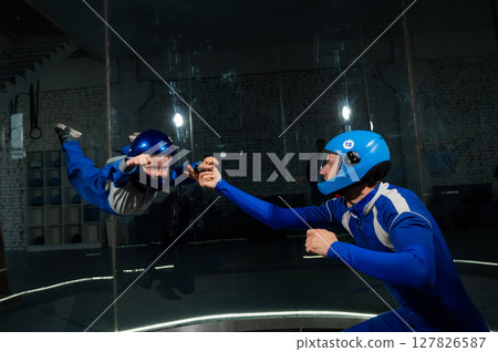 A man teaches a boy to fly in a wind tunnel. Lack of gravity. 127826587