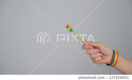 Woman wearing bracelet holds toothbrush with rainbow flag. Woman wearing bracelet holds toothbrush with rainbow flag. 127826691