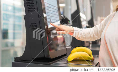 Faceless woman using self-checkout technology at grocery store.  127826806
