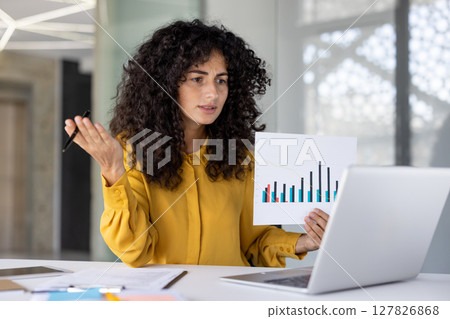 Businesswoman financier demonstrates and shows revenue graph at online conference meeting. Woman serious and focused at online presentation talking about company achievement results. 127826868