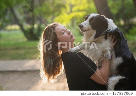 Young Caucasian woman hugging her border collie dog while walking in the park. Young Caucasian woman hugging her border collie dog while walking in the park. 127827009