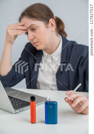 A woman demonstrates different types of cigarettes. An e-cigarette, a disposable vape, and a regular cigarette. A woman demonstrates different types of cigarettes. An e-cigarette, a disposable vape, and a regular cigarette. 127827017