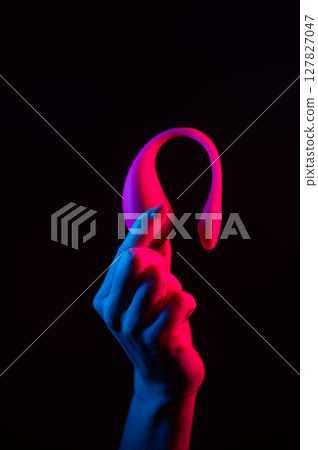 Woman holding a vibrator in neon pink and blue light. 127827047