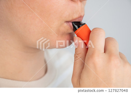 Caucasian woman smoking disposable vape.  127827048