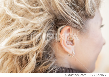 Close-up of a hearing aid on the ear of a young Caucasian woman.  127827077