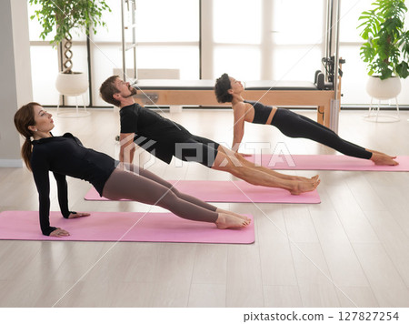 Two women and a man are doing yoga in the studio. Two women and a man are doing yoga in the studio. 127827254