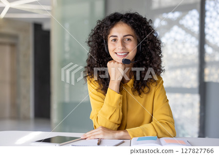 A friendly customer service representative smiles while working, showing her support and helpfulness for customers at their desk. 127827766