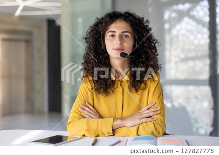 Webcam view, serious focused woman looking at camera with headset, businesswoman at workplace working inside office, listening to conversation remote conference. 127827778