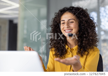 Hispanic businesswoman using headset, engaging in virtual meeting. She is in office environment, smiling and gesturing interacting. Represents communication, customer service, remote work Hispanic businesswoman using headset, engaging in virtual meeting. She is in office environment, smiling and gesturing interacting. Represents communication, customer service, remote work 127827845