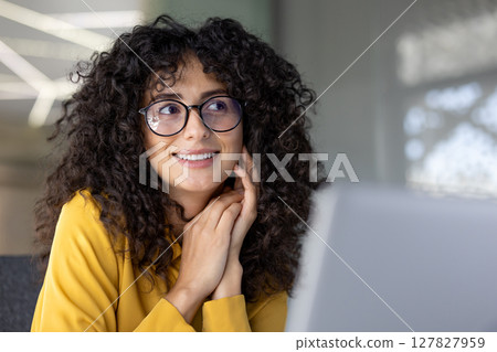 Happy dreamy woman close-up at workplace inside office, businesswoman in glasses and with curly hair smiling and satisfied with work. 127827959