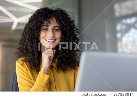 A beautiful woman smiles as she works on a laptop, looking cheerful and content, enjoying a moment of productivity. A beautiful woman smiles as she works on a laptop, looking cheerful and content, enjoying a moment of productivity. 127828014