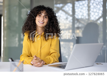 Successful woman at workplace inside office. Businesswoman smiling happily and looking at camera, office worker cheerfully working with laptop, portrait. 127828065