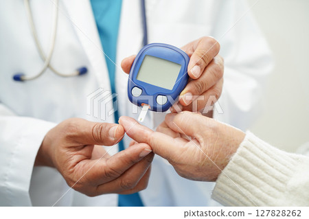 Asian doctor using digital glucose meter for check sample blood sugar level to treatment diabetes. Asian doctor using digital glucose meter for check sample blood sugar level to treatment diabetes. 127828262