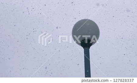 lamppost during snowfall in winter. winter snowstorm on the background of a lamppost in daytime. Blizzard in winter. lamppost during snowfall in winter. winter snowstorm on the background of a lamppost in daytime. Blizzard in winter. 127828337