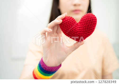 Asian woman holding LGBT heart with rainbow flag. 127828349