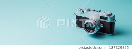 Vintage analog camera resting on a vibrant light blue backdrop, evoking nostalgia and the timeless appeal of classic photography 127829835