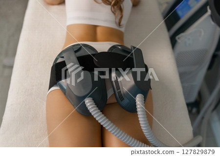 Woman getting treatment on buttocks to burn fat, build muscles and remove cellulite. Professional beauty salon 127829879