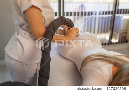 Woman in special white suit getting anti cellulite massage in a spa salon. LPG, and body contouring treatment in clinic.Reset body weight with LPG massage. Woman in special white suit getting anti cellulite massage in a spa salon. LPG, and body contouring treatment in clinic.Reset body weight with LPG massage. 127829896