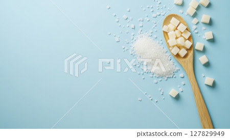 Wooden spoon with sugar cubes and granulated sugar on blue background, promoting sugar free lifestyle for better health 127829949