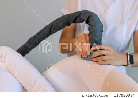 Woman in special white suit getting anti cellulite massage in a spa salon. LPG, and body contouring treatment in clinic.Reset body weight with LPG massage.  127829954