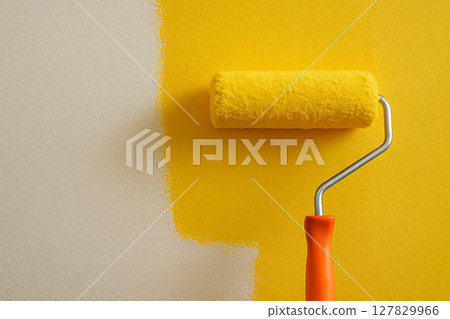 Paint roller painting a wall with yellow paint 127829966