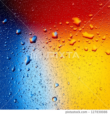 Colorful water droplets on vibrant blue, red, and yellow surface 127830086