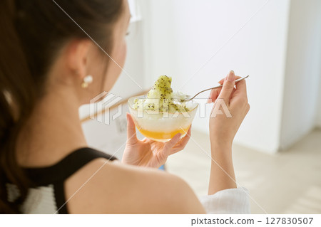 Lifestyle of a smiling young woman eating shaved ice and enjoying summer Lifestyle of a smiling young woman eating shaved ice and enjoying summer 127830507