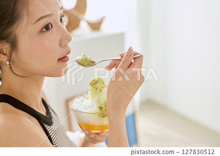 一位微笑的年輕女子吃刨冰享受夏日的生活方式 127830512