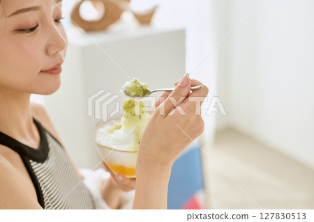 Lifestyle of a smiling young woman eating shaved ice and enjoying summer Lifestyle of a smiling young woman eating shaved ice and enjoying summer 127830513