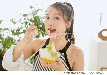 Lifestyle of a smiling young woman eating shaved ice and enjoying summer 127830522