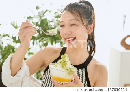 一位微笑的年輕女子吃刨冰享受夏日的生活方式 127830524