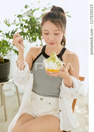 一位微笑的年輕女子吃刨冰享受夏日的生活方式 127830525