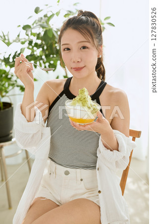 一位微笑的年輕女子吃刨冰享受夏日的生活方式 127830526