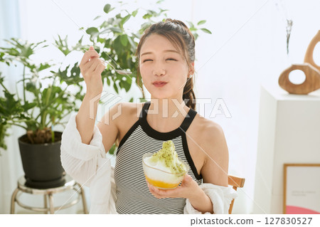 一位微笑的年輕女子吃刨冰享受夏日的生活方式 127830527