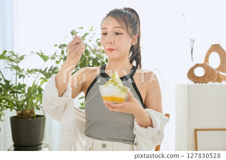一位微笑的年輕女子吃刨冰享受夏日的生活方式 127830528