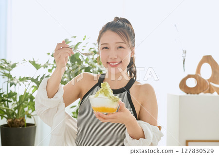 一位微笑的年輕女子吃刨冰享受夏日的生活方式 127830529
