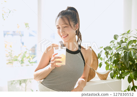 夏日清爽的年輕女子在房間裡喝檸檬水 127830552