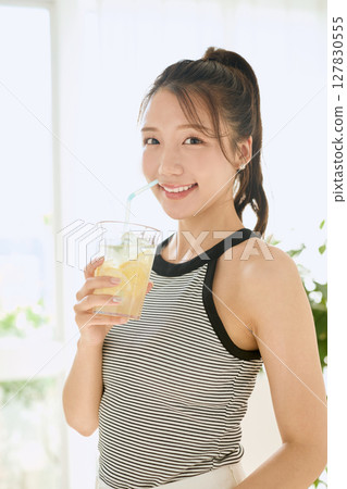 Summer refreshing young woman drinking lemonade in room 127830555